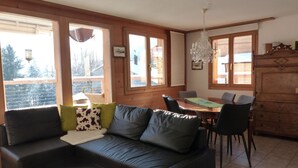 A cozy living room with a dark leather sofa, a round coffee table, and a dining area with a wooden table and chairs. - Strubelblick EG by Interhome (Lenk)