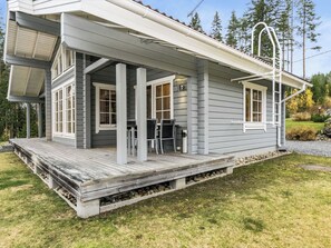 Ein zweistöckiges Haus mit einer Veranda, großen Fenstern und einem Steinfundament.