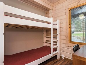 A bunk bed with a red mattress in a wooden cabin room.