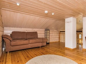 Ein Zimmer mit Holzboden, einer Holzdecke, einem braunen Sofa und einem weißen Teppich.