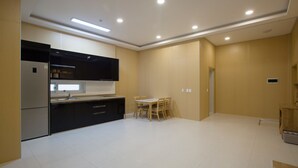 A modern kitchen with black cabinets, a stainless steel refrigerator, and a dining area with a table and chairs. - The Mare Pool Villa Pension (Taean)