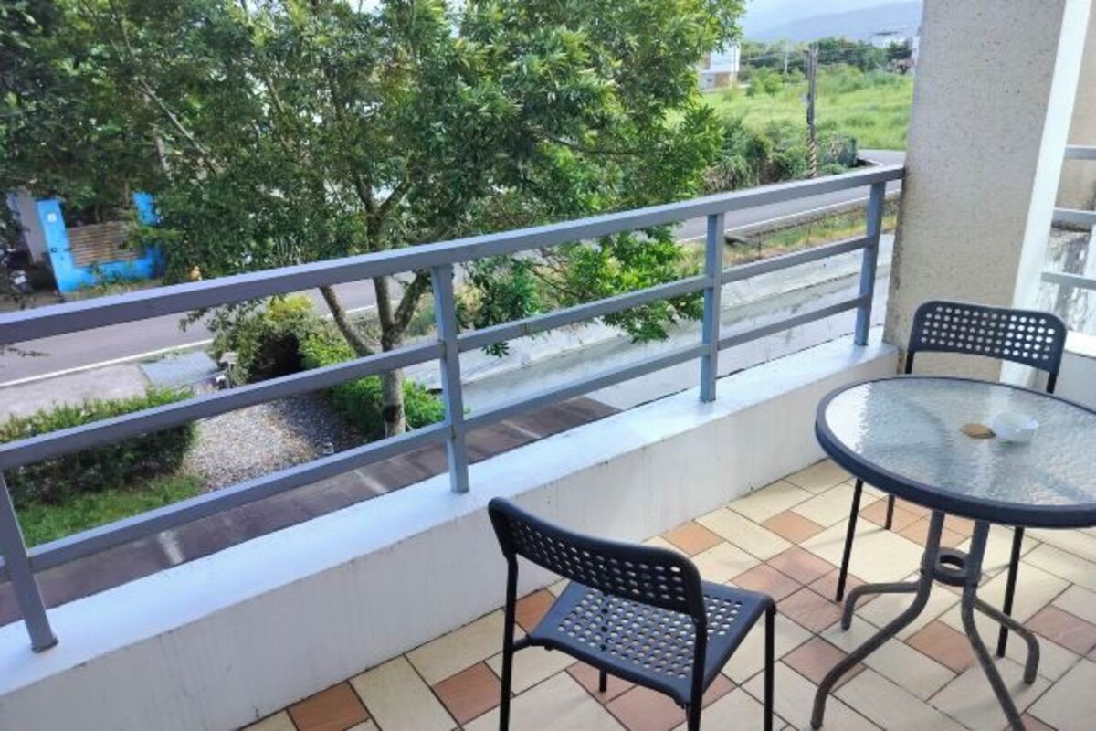 A balcony with a metal railing, two chairs, and a round table.