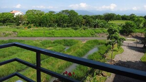 A view from a balcony overlooking a lush landscape with a river, greenery, and a distant mountain range. - Mei Shiou BB (Dongshan)