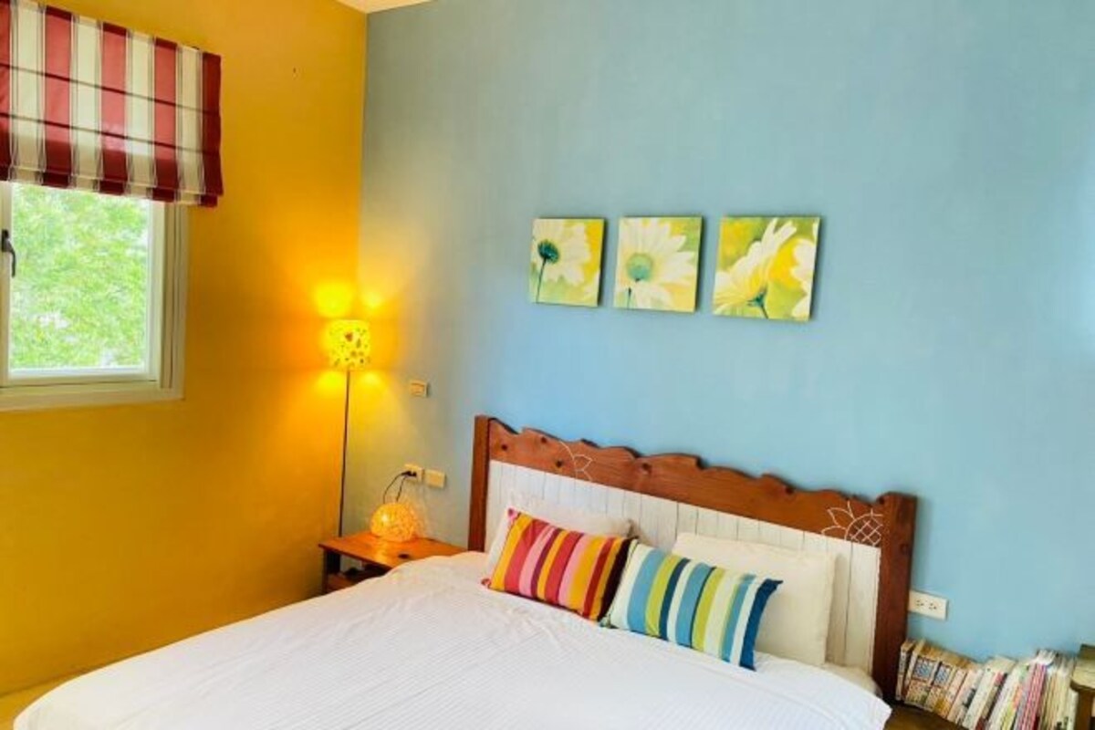 A bedroom with a bed, a nightstand, a lamp, and three wall art pieces.