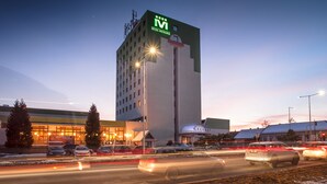 Un hotel con un llamativo letrero 'HOTEL METROPOL', diseño moderno y un estacionamiento con coches.