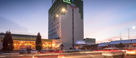 A hotel with a prominent 'HOTEL METROPOL' sign, a modern design, and a parking lot with cars.