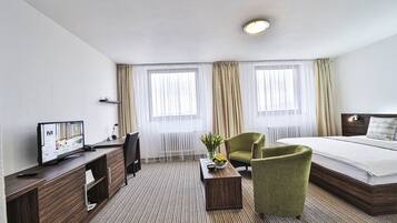 Ett hotellrum med en säng, ett skrivbord med en tv, en stol och ett soffbord.