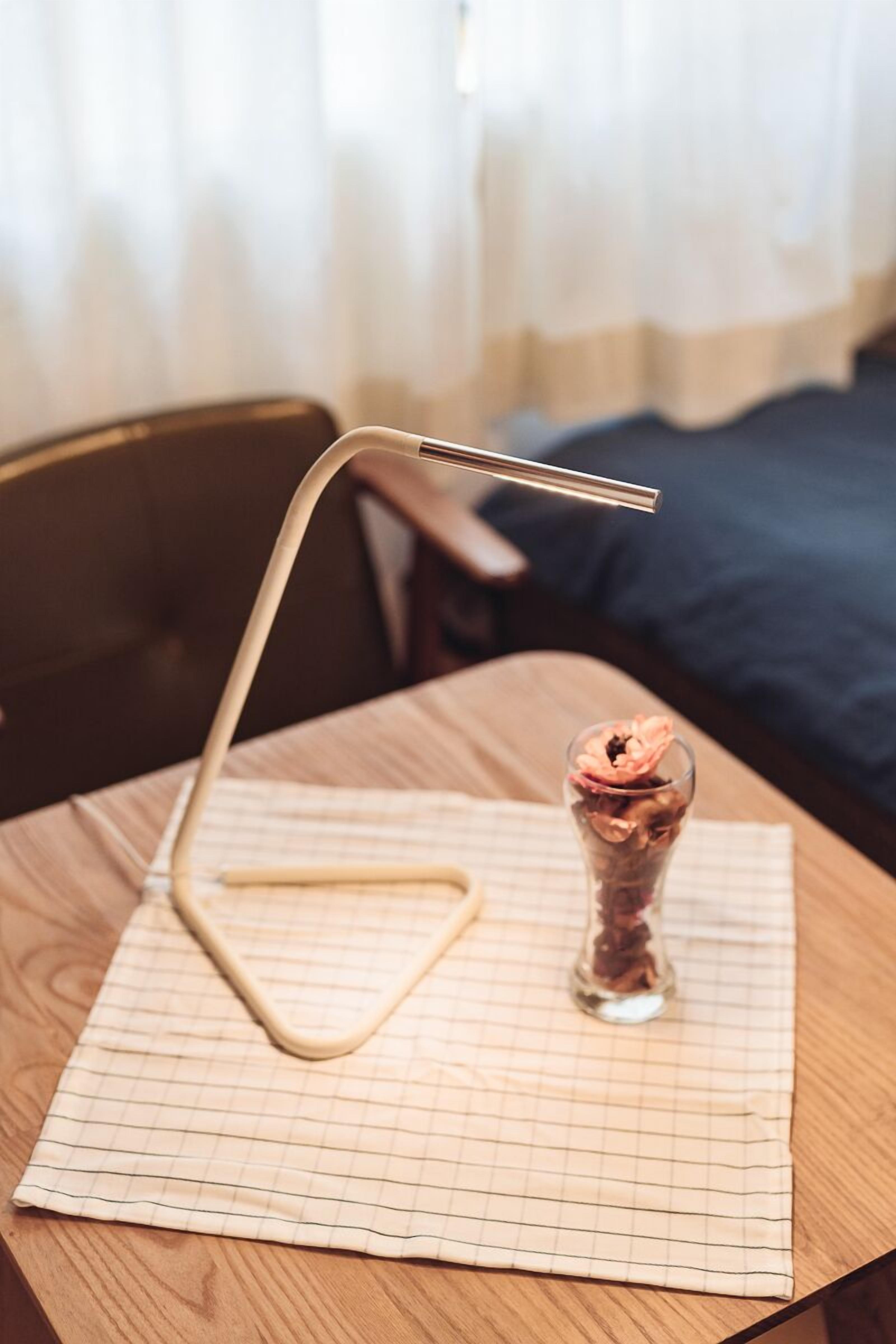 Una mesa con un mantel individual estampado en cuadrícula, un vaso transparente con un líquido rosado y un soporte de metal.