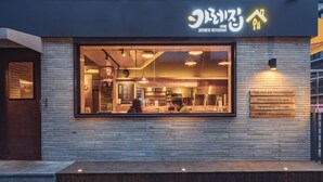 Un restaurante japonés con fachada moderna, un amplio ventanal que muestra el interior y un letrero que anuncia las ofertas del día.