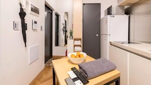 Una cocina compacta con refrigerador, microondas y un tazón de fruta en la encimera.