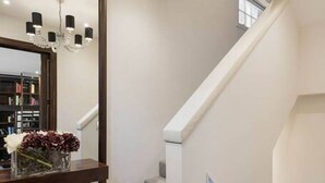 A staircase with a modern design, a chandelier, and a mirror reflecting a room with a patterned floor. - Private Knightsbridge Mews House | Harrods 1min, Parking & Top 5% Rated (Knightsbridge)