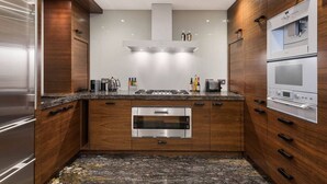 A modern kitchen with wooden cabinets, stainless steel appliances, and a granite countertop. - Private Knightsbridge Mews House | Harrods 1min, Parking & Top 5% Rated (Knightsbridge)