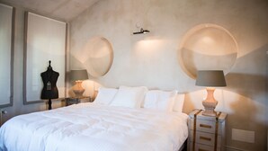 Ein Schlafzimmer mit einem großen Bett, zwei Nachttischen mit Lampen, einer Mannequin und einer Wandleuchte.