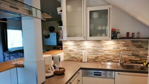 Una cocina moderna con armarios blancos, protector contra salpicaduras de piedra y lavavajillas integrado.