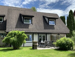 A two-story house with a tiled roof, a balcony, and a patio area with outdoor furniture. - Ferienwohnung Gartenblick (Aalen)