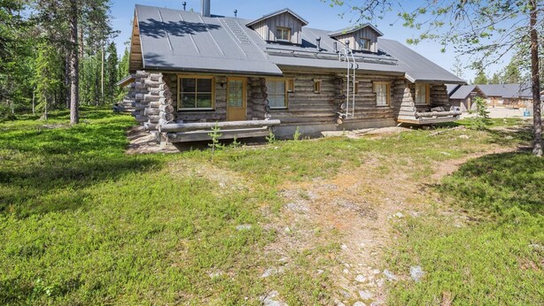 A log cabin with a stone foundation, a large window, and a chimney.