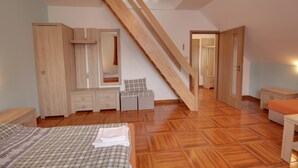 A bedroom with a wooden staircase, a bed, a wardrobe, a mirror, and a small table. - Guest House Pod Hajkem (Horni Branna)