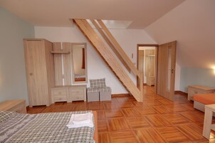 Un dormitorio con una escalera de madera, una cama, un armario, un espejo y una mesita.