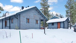 A wooden cabin with a porch, surrounded by snow-covered ground and trees. - Tunturitähti by Interhome (Äkäslompolo)
