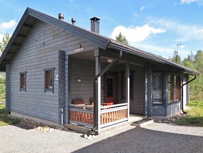 A two-story cabin with a porch, a chimney, and a small deck area.