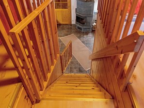 A wooden staircase with a handrail leading to a tiled floor.