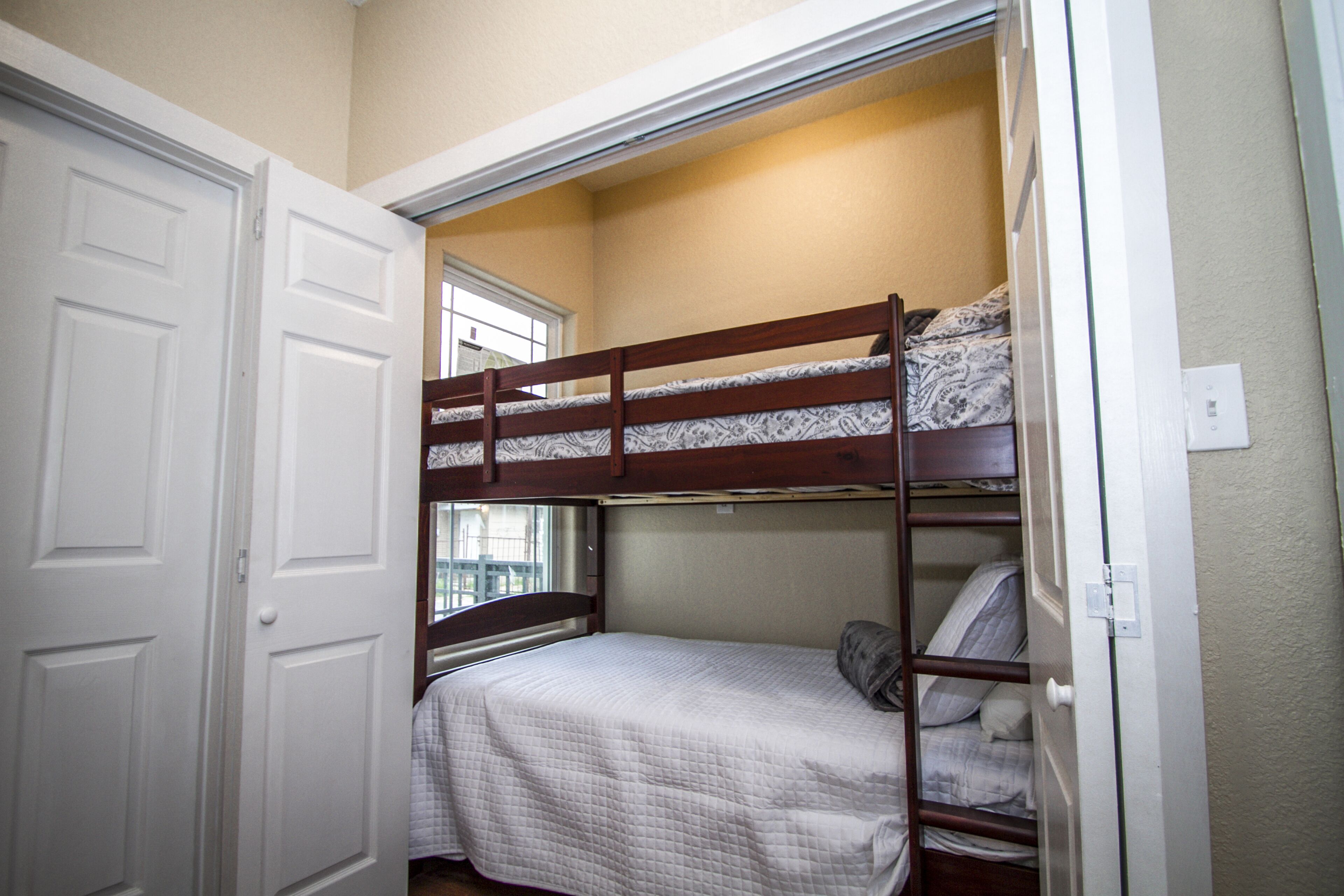 A bunk bed room with a white door and a window.