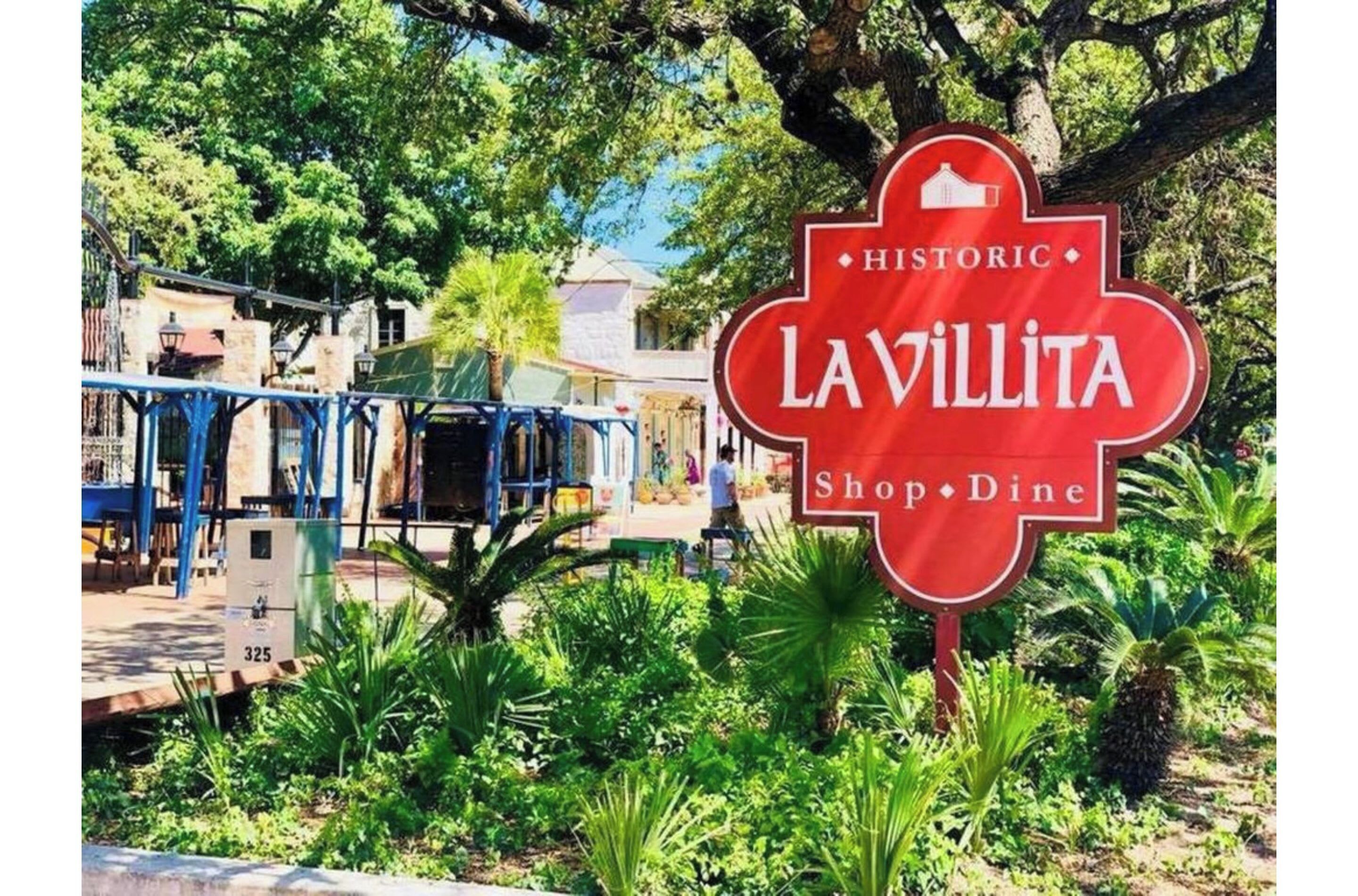 Un panneau rouge sur lequel on peut lire « LAVILLITA Shop · Dine » et « HISTORIC », entouré de verdure et avec un bâtiment en arrière-plan.