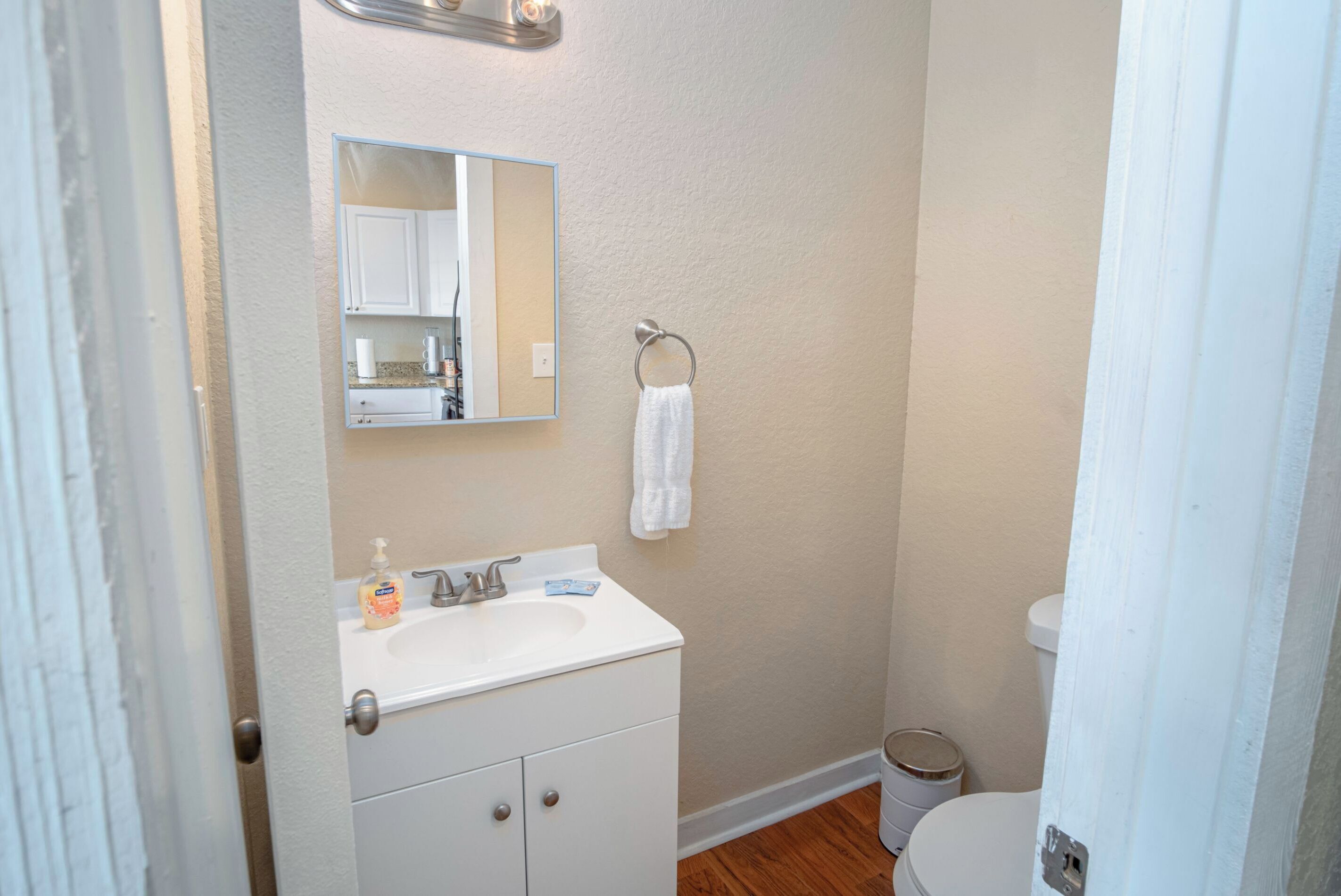 A bathroom with a white sink, mirror, and toilet.