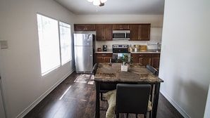 A kitchen with wooden cabinets, a stainless steel refrigerator, a microwave, and a ceiling fan. - Cozy Remodeled 2br/2ba Near Downtown Sleeps 8 (San Antonio)