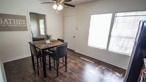 A dining area with a wooden table, four chairs, a ceiling fan, and a window with blinds. - Cozy Remodeled 2br/2ba Near Downtown Sleeps 8 (San Antonio)