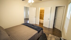 A bedroom with a bed, a ceiling fan, and a bathroom visible through an open door. - Cozy Remodeled 2br/2ba Near Downtown Sleeps 8 (San Antonio)