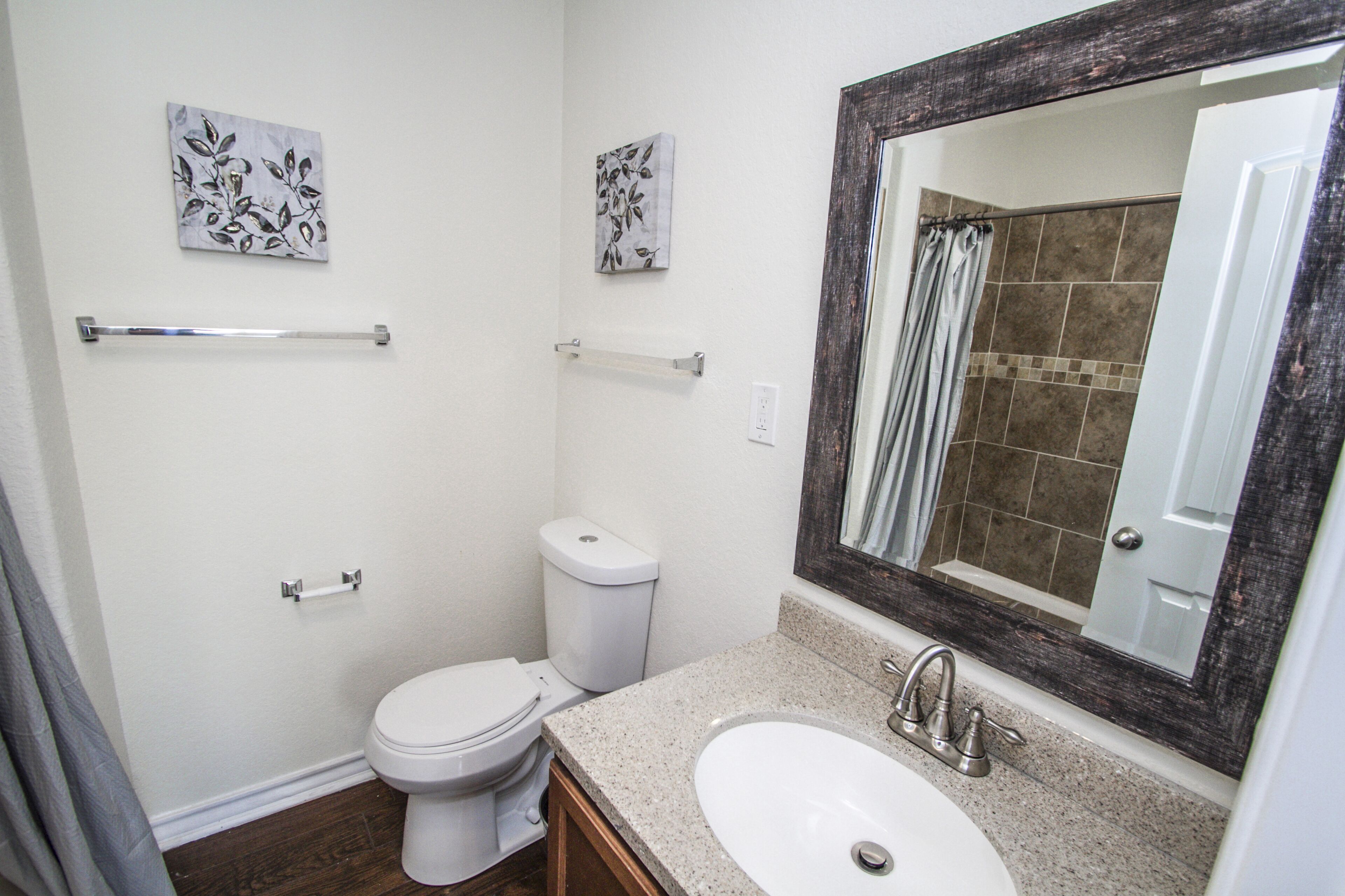 A bathroom with a white toilet, a sink with a mirror, and two wall-mounted towel racks.