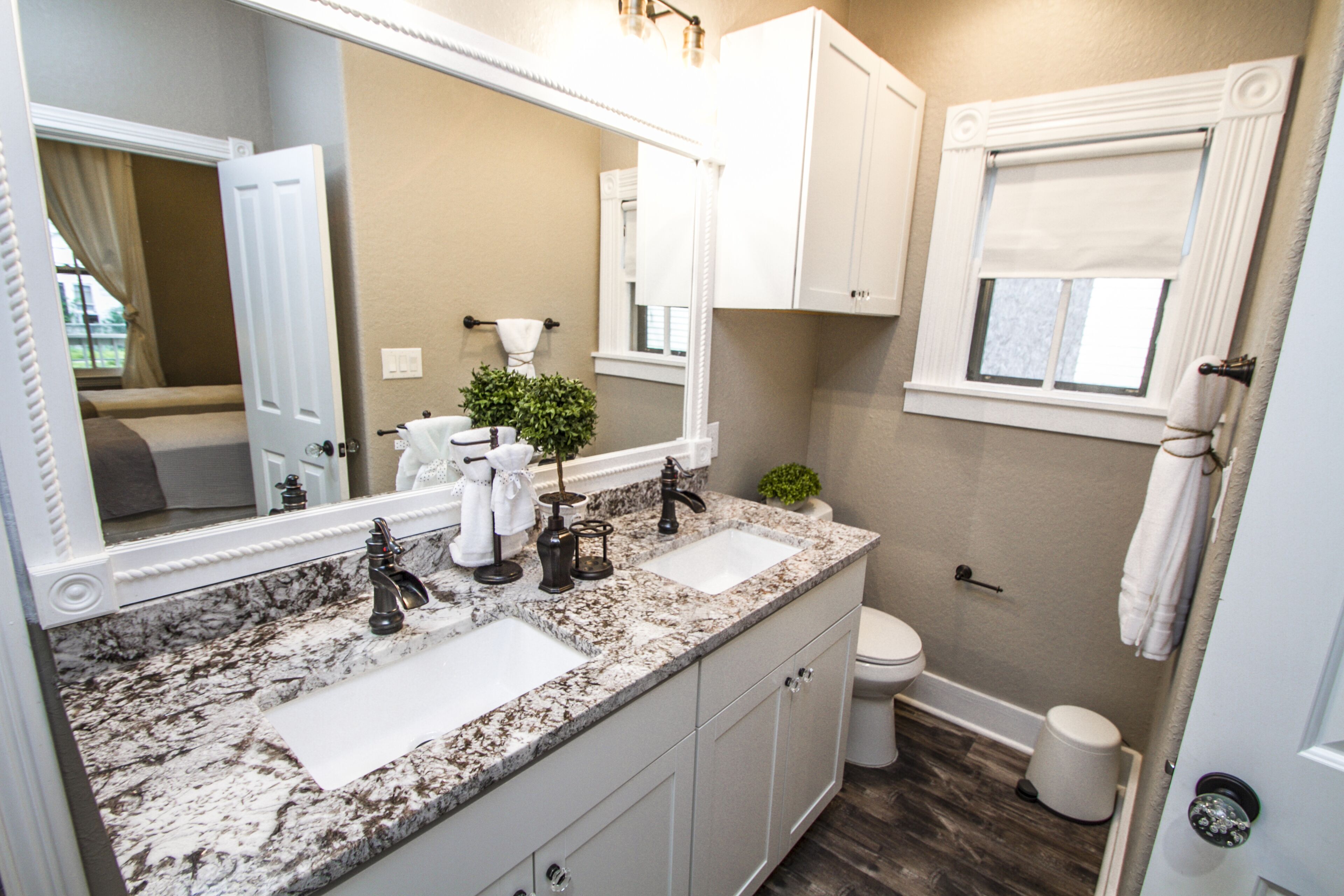 A bathroom with two sinks, a large mirror, and a toilet.