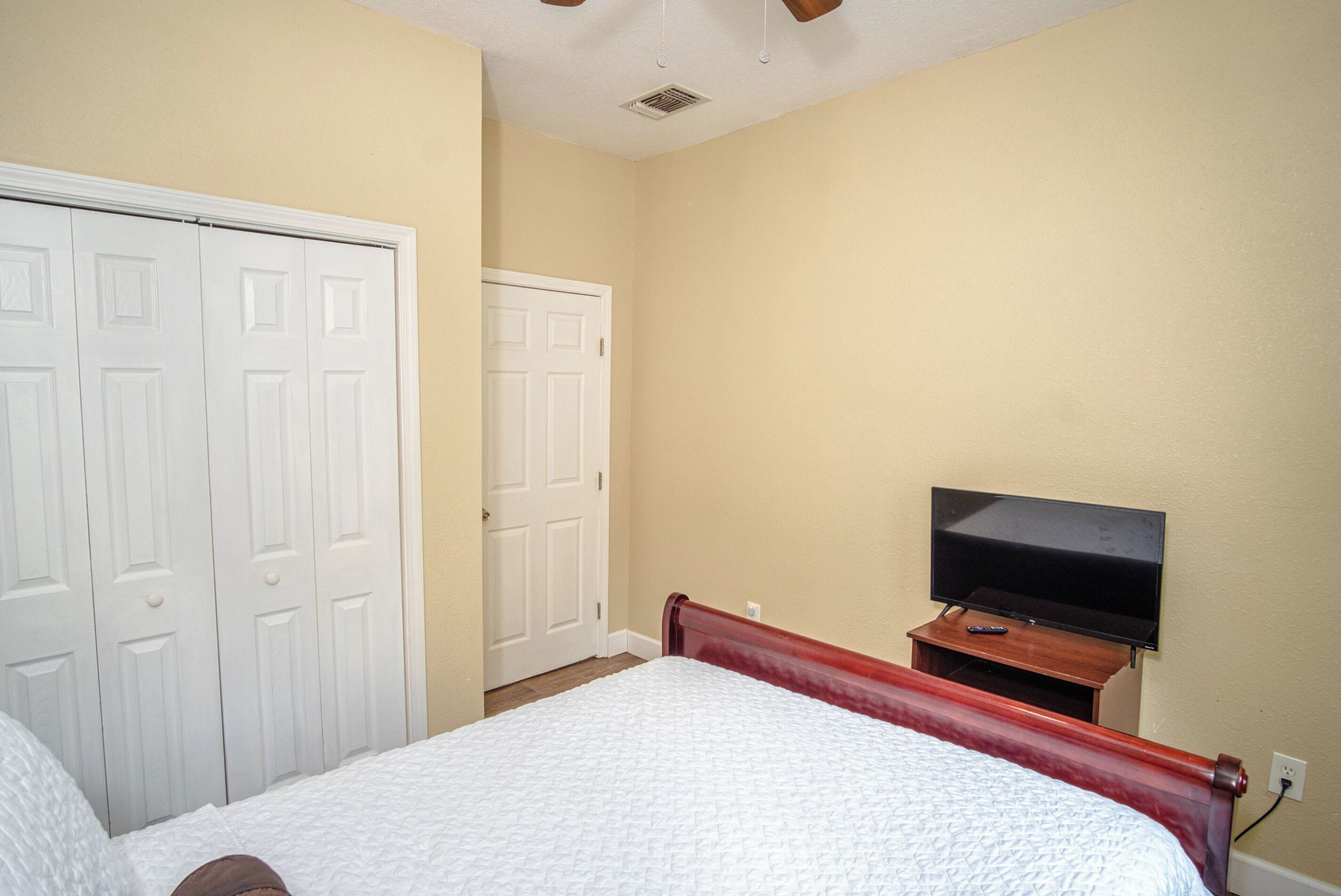 Une chambre à coucher avec un lit, un téléviseur posé sur un meuble et une armoire.