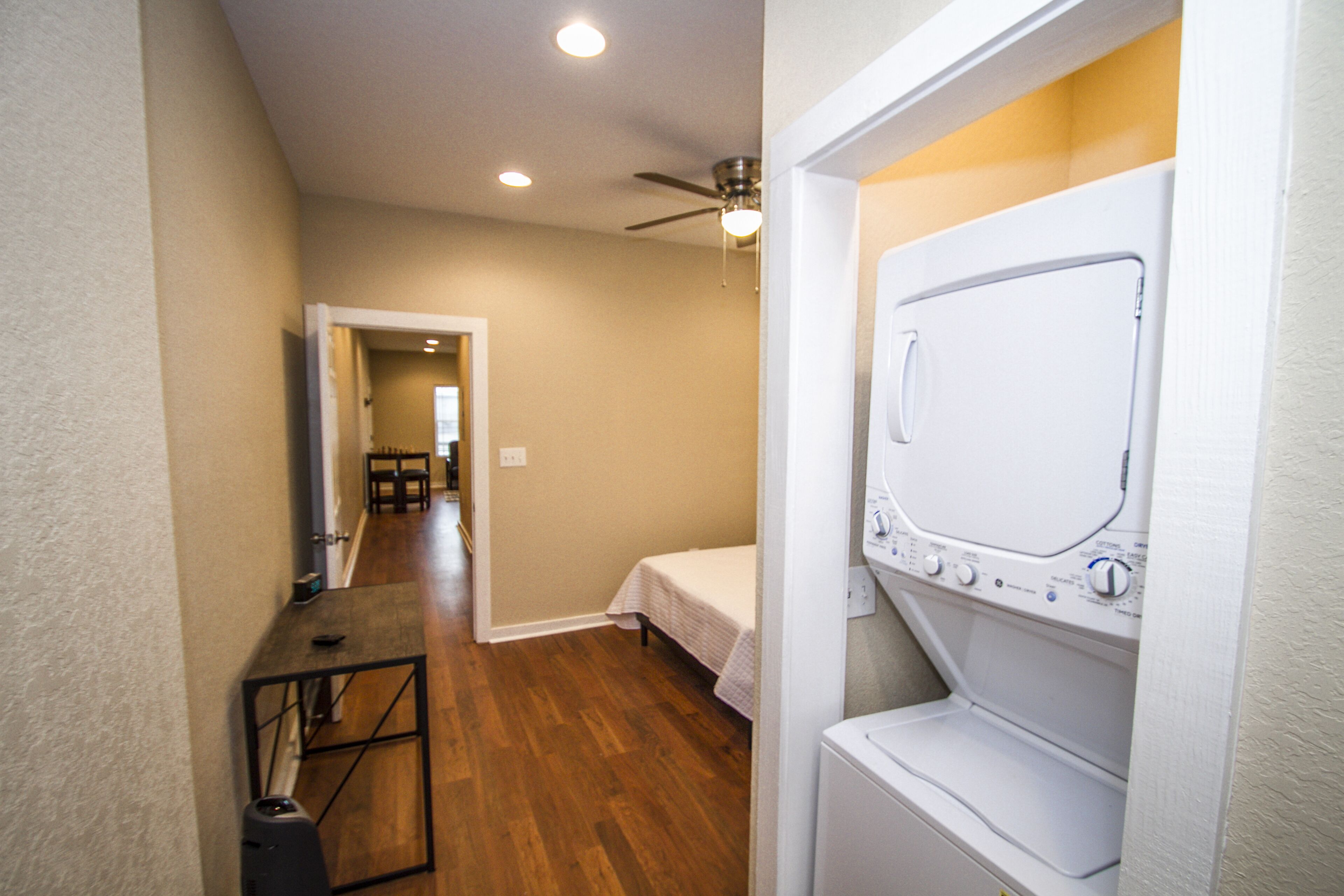A laundry room with a washing machine, a ceiling fan, and a wooden table.