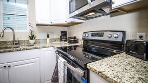 A kitchen with white cabinets, a granite countertop, a black stove, a microwave, and a toaster. - Renovated 2br/2ba Near Downtown (San Antonio)