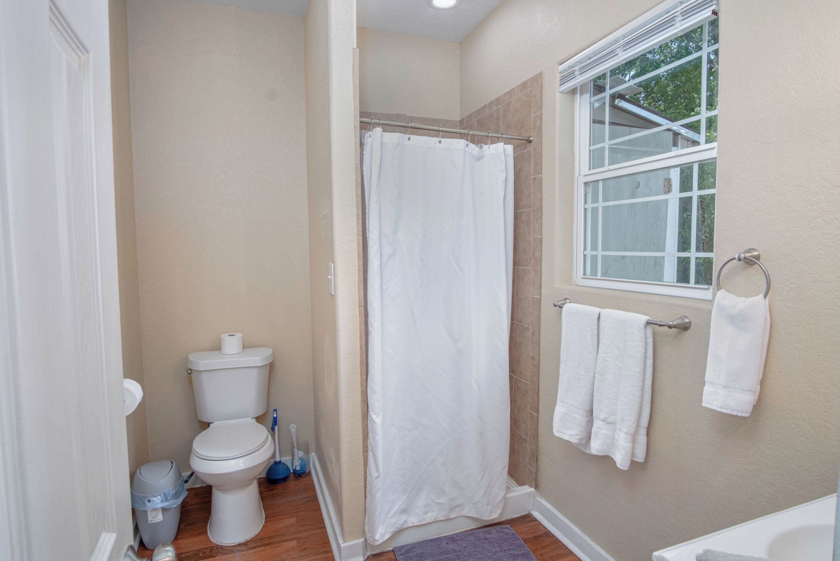 A bathroom with a toilet, shower curtain, and a bathtub.
