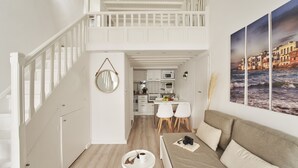 Un interior modern amb un dormitori tipus loft, una zona de menjador i una cuina.