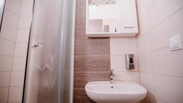 A bathroom with a glass shower door, a white sink, and a mirror cabinet.