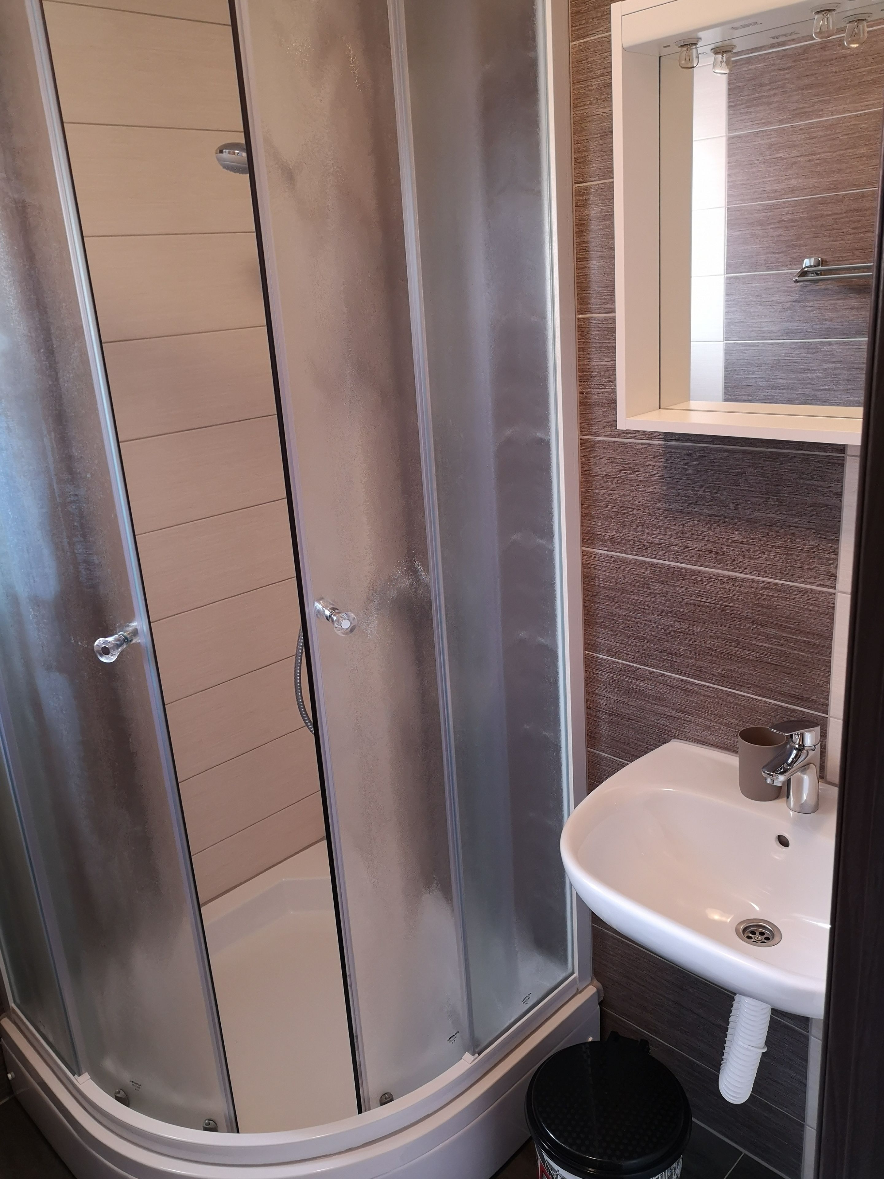 Un baño con ducha de vidrio, un lavamanos blanco y un espejo encima.