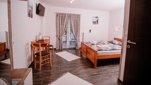 A bedroom with a wooden bed, a desk with a chair, a window with curtains, and a radiator. - House Karakas (Plitvicka Jezera)