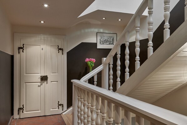 A staircase with white balusters and a door with a number '6' on it. - Mostecká 12 Residence (Prague)