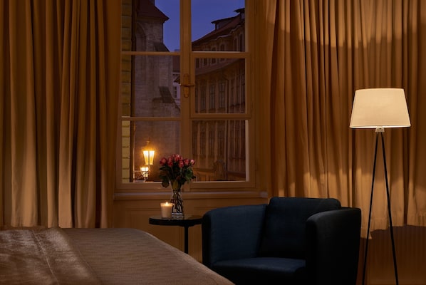 Une chambre d’hôtel avec un lit, une chaise, une table ornée d’un vase de fleurs et une lampe.