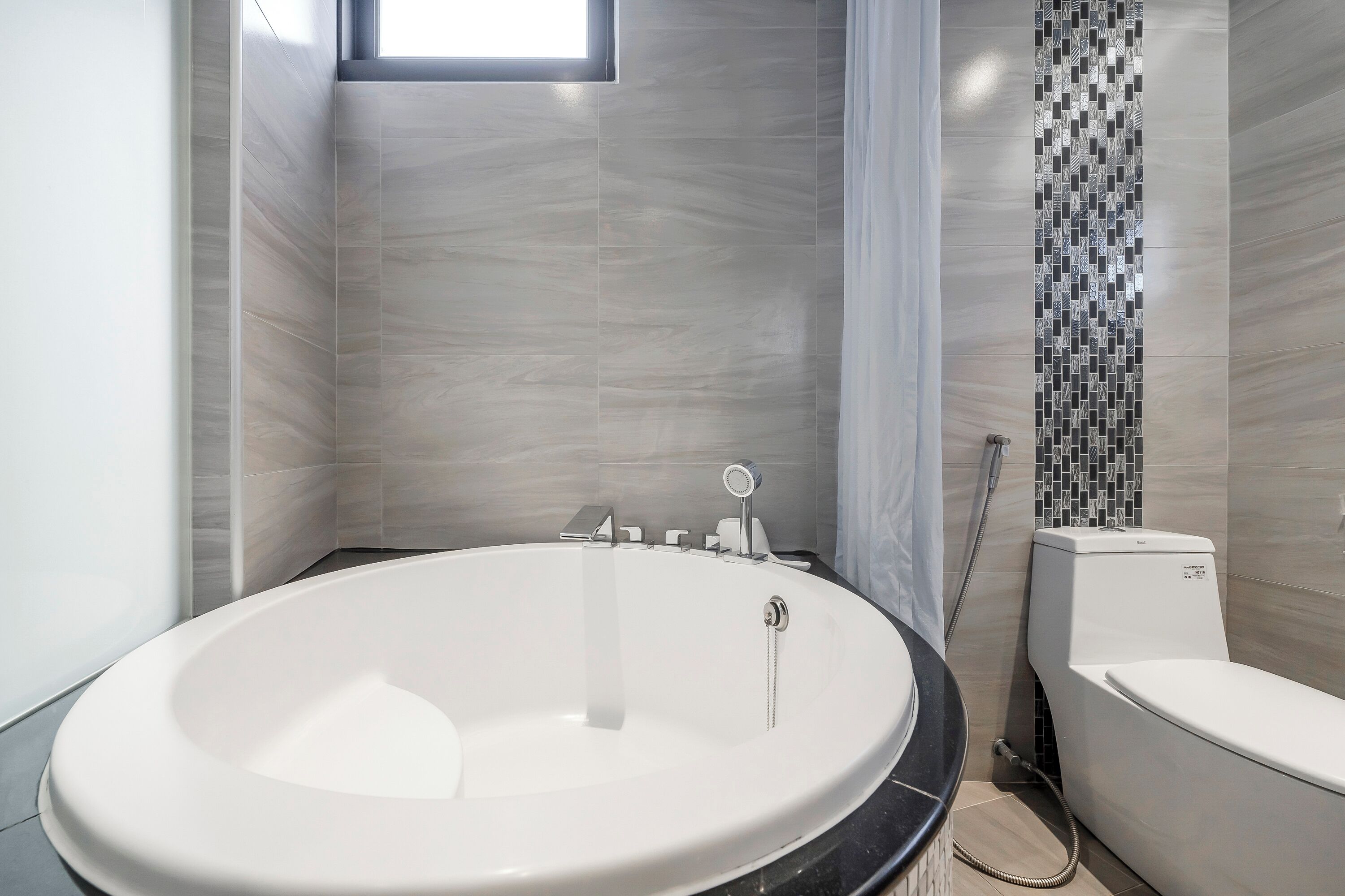 Un baño moderno con una bañera independiente, inodoro y zona de ducha.