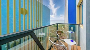 A balcony with a glass railing, a wooden table, and a white chair. - Pacific Inn (Hengchun)