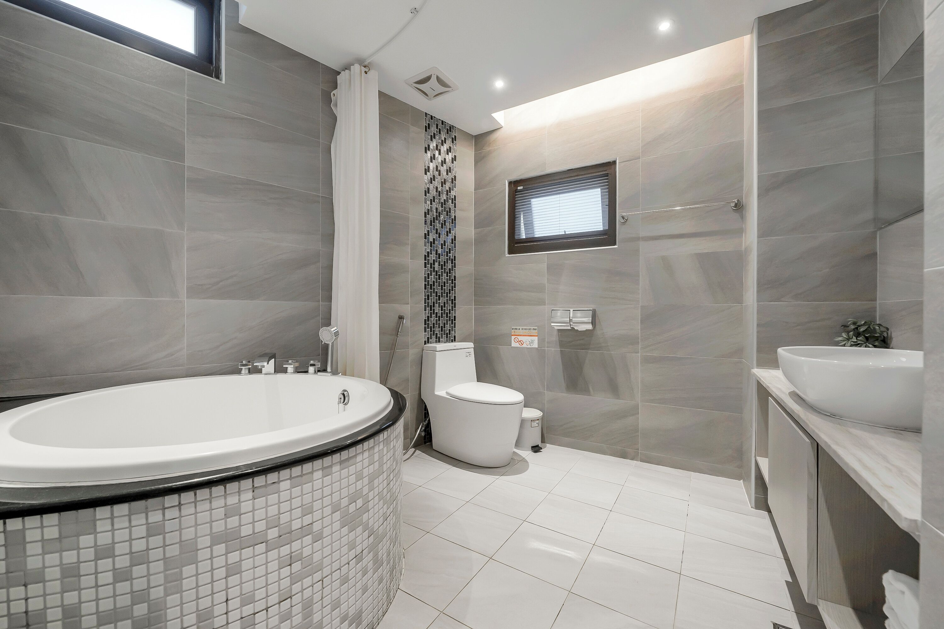 A modern bathroom with a large bathtub, toilet, and sink.