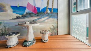 A room with a mural of a beach scene, a wooden floor, and two mushroom-shaped tables. - Pacific Inn (Hengchun)