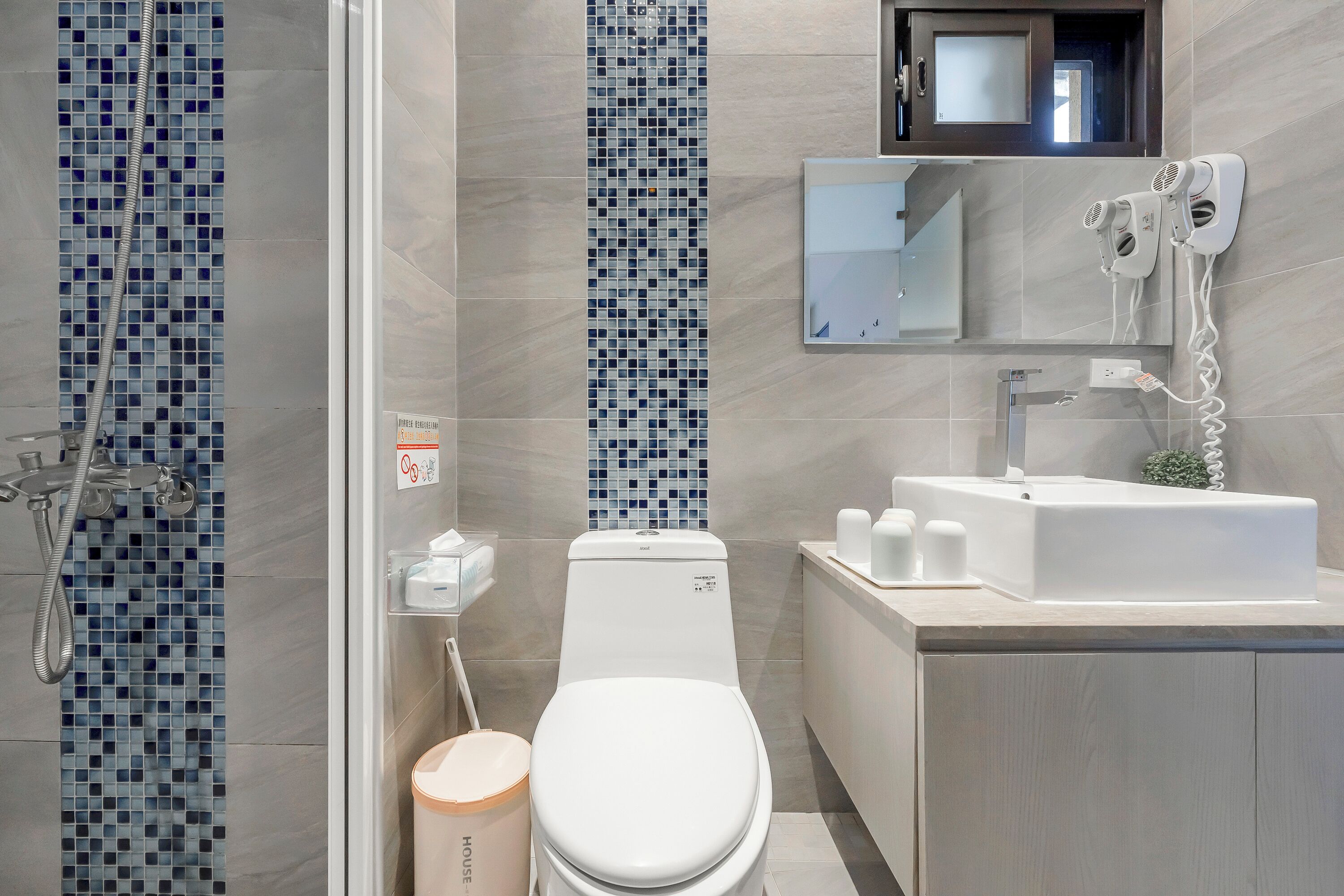 Een moderne badkamer met douche, toilet, wastafel en spiegel.