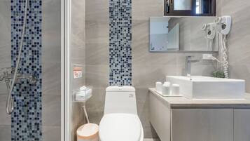 Een moderne badkamer met douche, toilet, wastafel en spiegel.