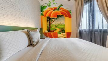 A neatly made bed with a patterned bedspread, a wall with a mural of a pumpkin and a landscape, and a window with sheer curtains.